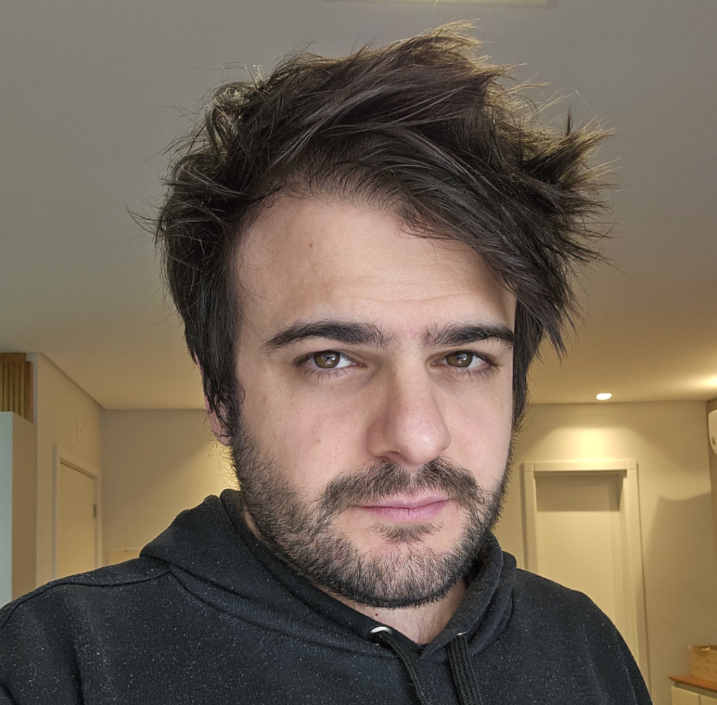 Portrait of Roger Laureano, with slightly messy hair, wearing a dark hoodie, in a well-lit indoor setting.